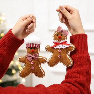 Close-up of plush gingerbread man couple ornaments hanging on a festive Christmas tree