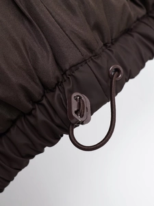 Close-up of brown quilted vest hem featuring adjustable elastic drawstring and plastic toggle
