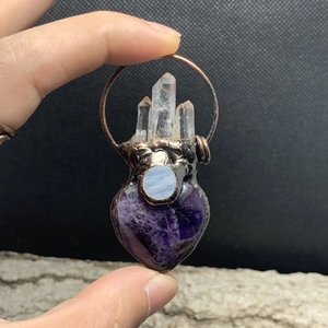 Detailed close-up of handmade bronze pendant with purple heart crystal and white quartz