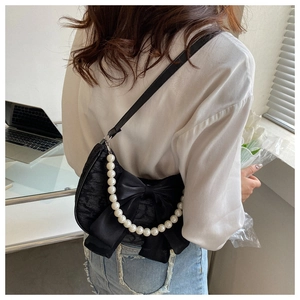 Rear view of black lace shoulder bag with bow and pearl chain on a model's shoulder