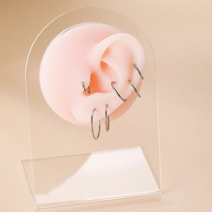 Set of six silver titanium hoop rings in various sizes displayed on a silicone ear model