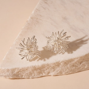 Détail de boucles d'oreilles feu d'artifice exposées sur une pierre naturelle texturée