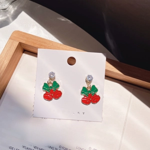 Macro shot of festive red bell earrings with green bows and sparkling zircons