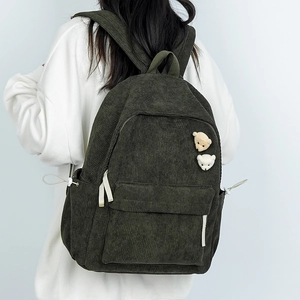 Dunkelgrüner Cord-Rucksack mit Bären-Broschen, an einem Modell für den Alltag