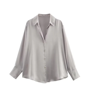 Détail de la texture satinée argentée sur une chemise à manches longues avec lustre