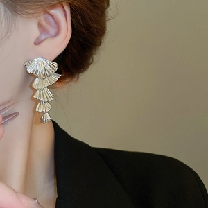 Detail of silver five-layer fan tassel earrings worn by a model in a black blazer