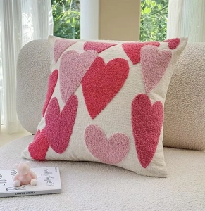Detail of pink tufted heart patterns on soft cream fabric pillow cover for home decor