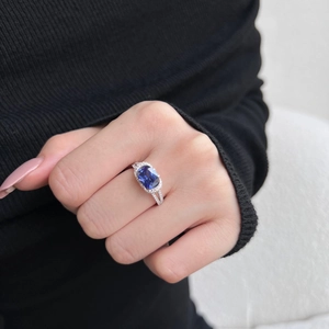 Detailed view of an S925 silver ring featuring a large blue cushion-cut gemstone on a finger