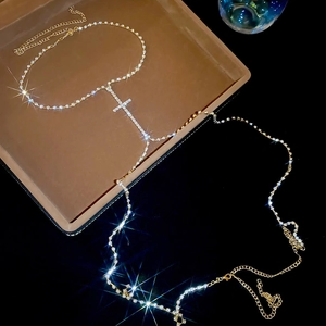 Close-up of sparkling rhinestone cross body chain with gold finish on jewelry tray