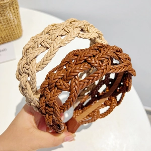 Close-up of beige and brown braided faux leather headbands showing woven texture detail