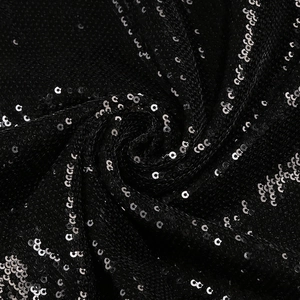 Close-up of black sequin fabric with shimmering 3D flower detail and spiral texture