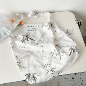 Close-up of artistic bamboo leaf print on a white canvas tote bag with soft lighting