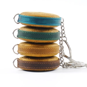 Vertical stack of leather mini tape measures with colorful stitched edges and keychains