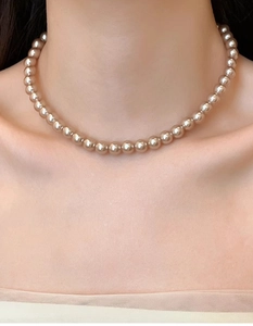 Close-up of elegant champagne pearl necklace on model's neckline showing lustrous texture