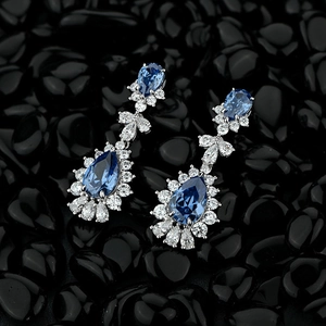 Luxury water drop blue crystal earrings with pavé diamonds on black stone background