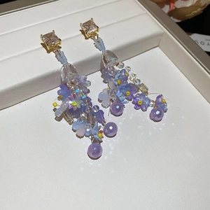 Macro shot of long floral tassel earrings with purple beaded petals and crystals