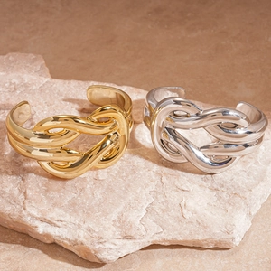 Close-up of gold and silver twisted knot bangles with polished metallic surface texture