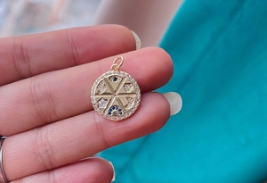 Macro shot of gold circular pendant with micro-pave blue and white zircon star moon design