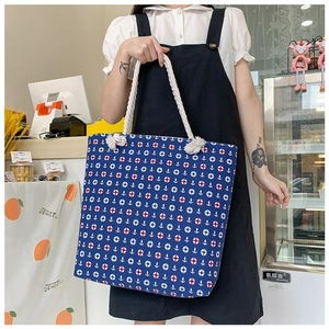 Detail of blue canvas tote bag with nautical anchor print and thick rope handles