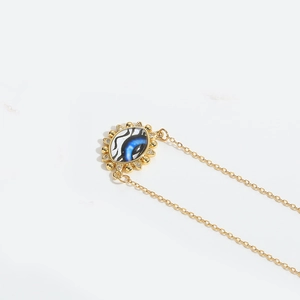 Detailed close-up of golden Devil's Eye pendant with blue enamel and zircon stones
