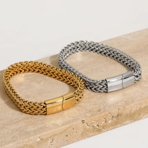 Elegant gold and silver woven mesh bracelets in stainless steel on a stone tray