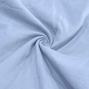Close-up of light blue linen shirt fabric showing detailed woven texture and soft drape