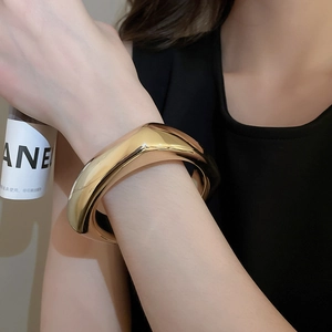 Gros plan d'un large bracelet géométrique en acrylique doré avec finition miroir polie