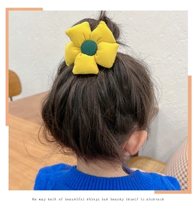 Close-up of yellow fabric sunflower hair tie worn on a child's ponytail
