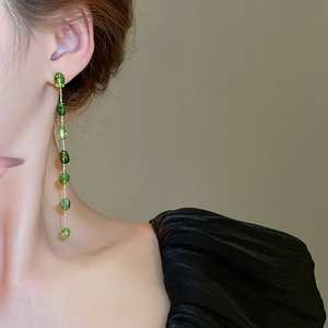 Detail showing elegant long green crystal bead drop earrings worn by a model