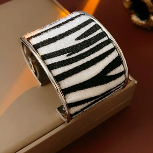 Detail of zebra print texture and silver metal edges on a wide open cuff bracelet
