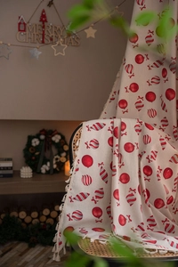 Detail of Christmas candy pattern curtain fabric with beige tassels on a rattan chair