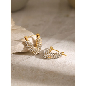 Détail macro de boucles d'oreilles en acier doré en V avec zircons pavés étincelants