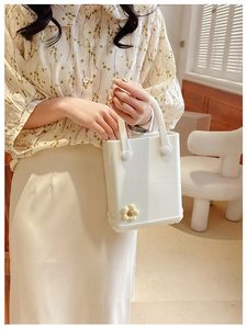 Weiße EVA-Gelee-Tasche mit gelbem Blumenanhänger von einem Model in der Hand gehalten