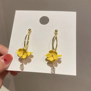 Close-up of yellow flower earrings with crystal teardrop pendant on white card