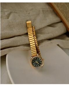 Macro shot of vintage gold ladies watch with deep green dial and fluted bezel on ceramic