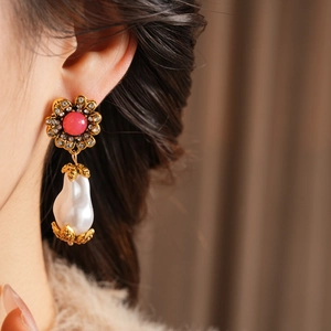 Close-up of golden vintage flower earrings with pink gemstones and pearls on model