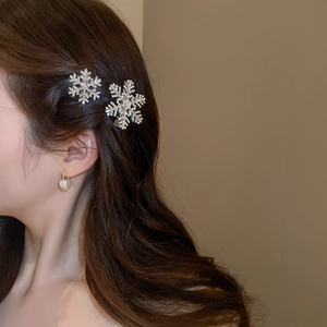 Detailed close-up of a sparkling snowflake hair clip with inlaid rhinestones on a model