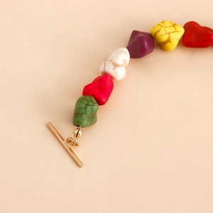 Detail of colorful irregular heart-shaped beads and gold metal toggle clasp closure