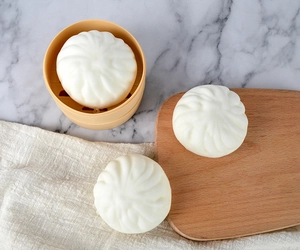 Detailed view of white PU squishy steamed bun toy on a realistic plastic steamer tray