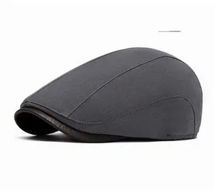 Detail of dark grey cotton linen flat cap showing woven texture and brown leather brim edge