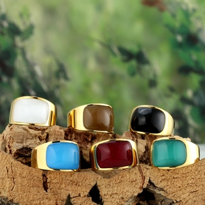 Polished gold stainless steel rings with colorful cat eye stones on rustic wood base