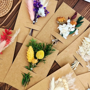 Close-up of assorted dried flower bouquets on kraft paper envelopes on a wooden desk