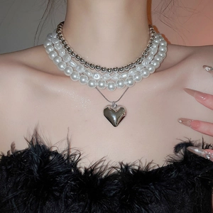 Gros plan détaillé d'un collier de perles à trois rangs avec pendentif cœur sur un mannequin