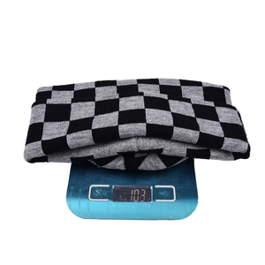 Detailed view of checkered knit hat weighing 103g on a blue digital scale