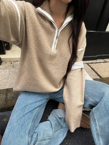 Close-up of camel knit sweater with white half-zip collar and striped sleeve detail