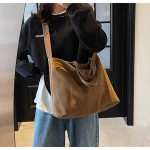 Detail of deep brown canvas tote bag featuring long shoulder strap and textured surface