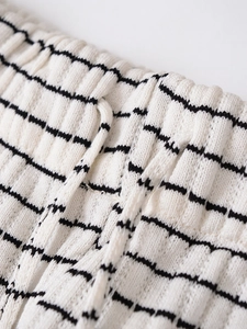 Détail d'un pantalon en maille rayée avec taille élastique et cordon de serrage
