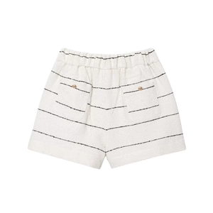 Dettaglio degli shorts in tweed con strisce nere e bottoni dorati sulle tasche posteriori