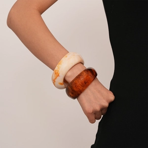 Close-up of amber and marble resin bangles on a model's wrist with minimalist style