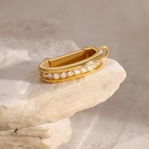 Macro shot of gold-plated U-shaped bikini connector with zircon inlay on natural stone